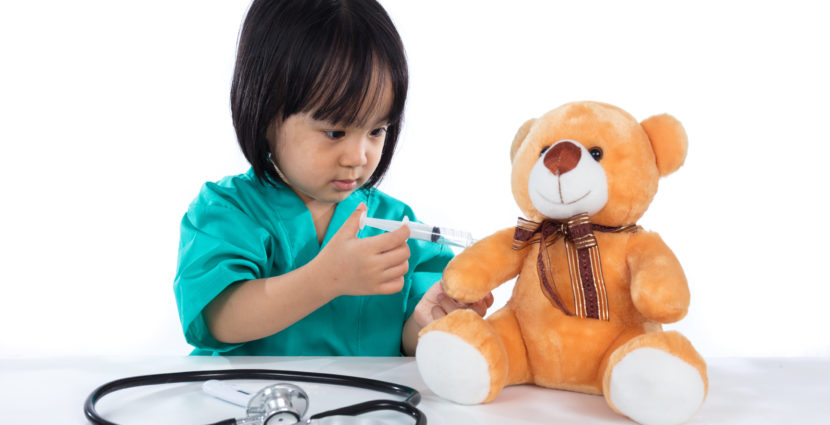 girl giving injection to teddy bear